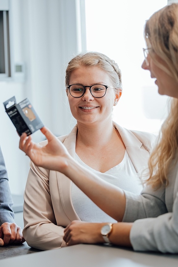 Zwei Frauen und ein Mann im Gespräch über ein Produkt